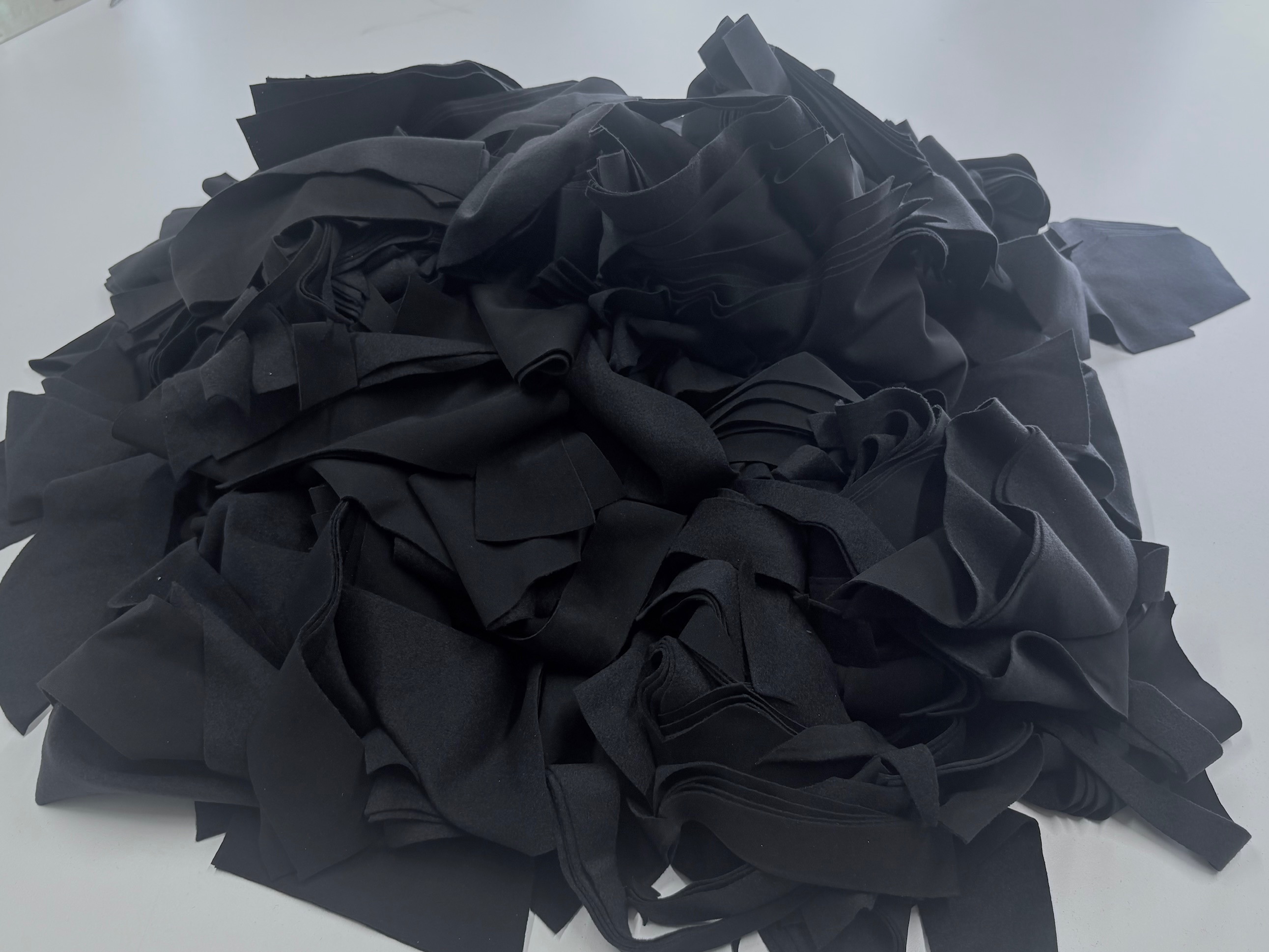 Mesa de corte en Negua con restos de tela negra en rollo. Gestión de residuos textiles de color pre-confección.